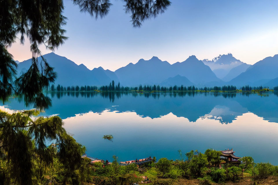 Twilight lake scene with mountains, pavilion, and lush trees