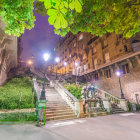 Classical architecture with columns, stairs, and period clothing in a scenic cityscape.