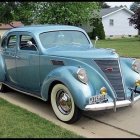 Vintage Blue Car Parked with Cognac Bottle and Glass in Front of White Building