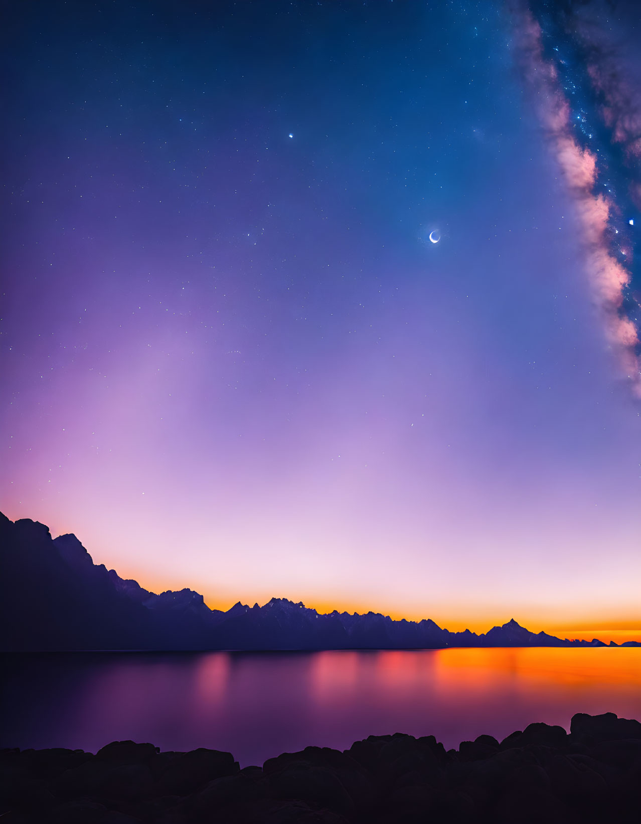 Twilight sky over silhouetted mountains with moon, star, and Milky Way reflected on water