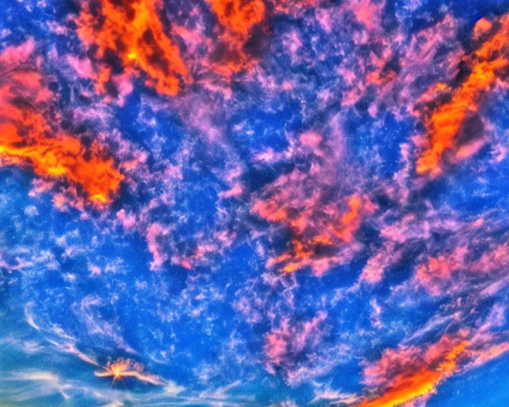 Colorful orange and pink clouds in a deep blue sky at sunset or sunrise