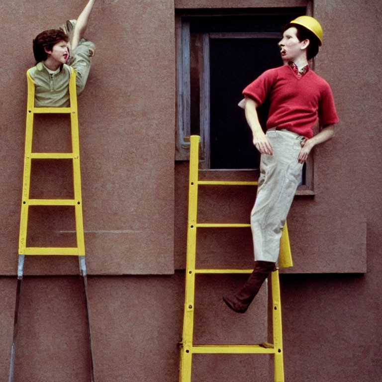 Two men on yellow ladders painting by window.