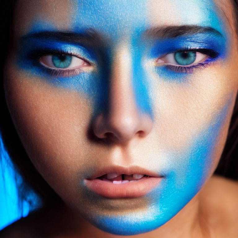 Person's Face with Dramatic Blue Makeup on Dark Background