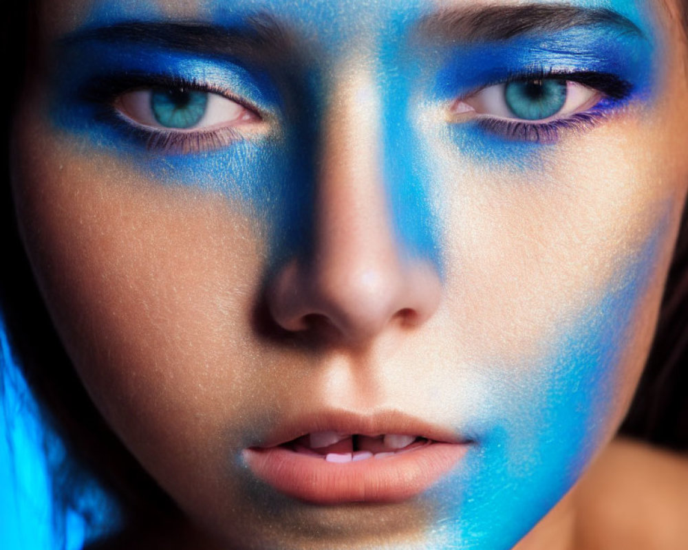 Person's Face with Dramatic Blue Makeup on Dark Background