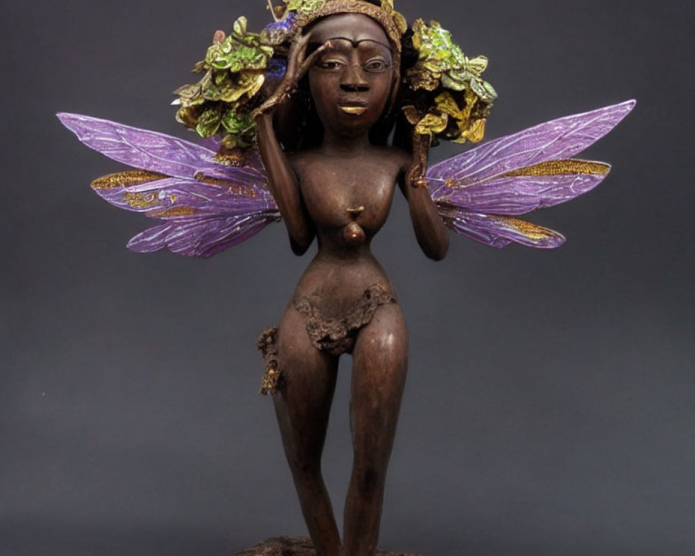 Fantasy female faerie figurine with purple wings and green headdress on dark background