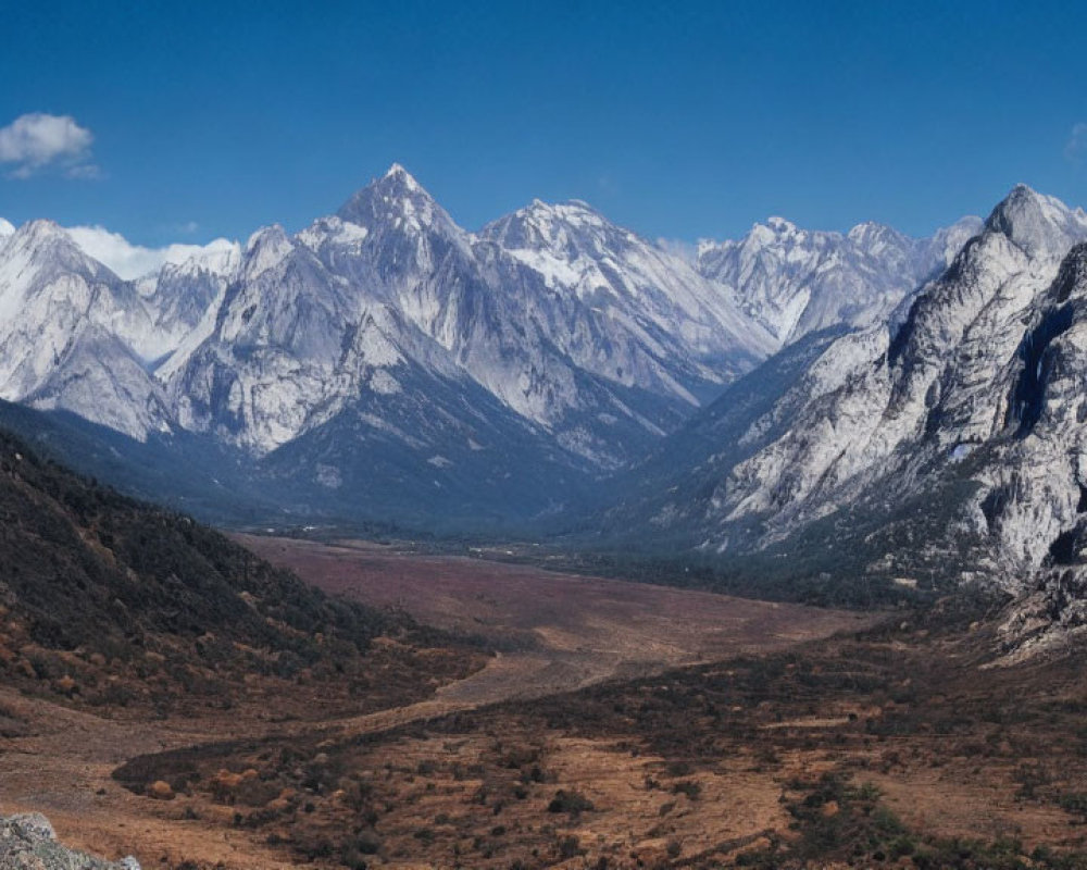 Snow-capped mountain range with valley and blue sky