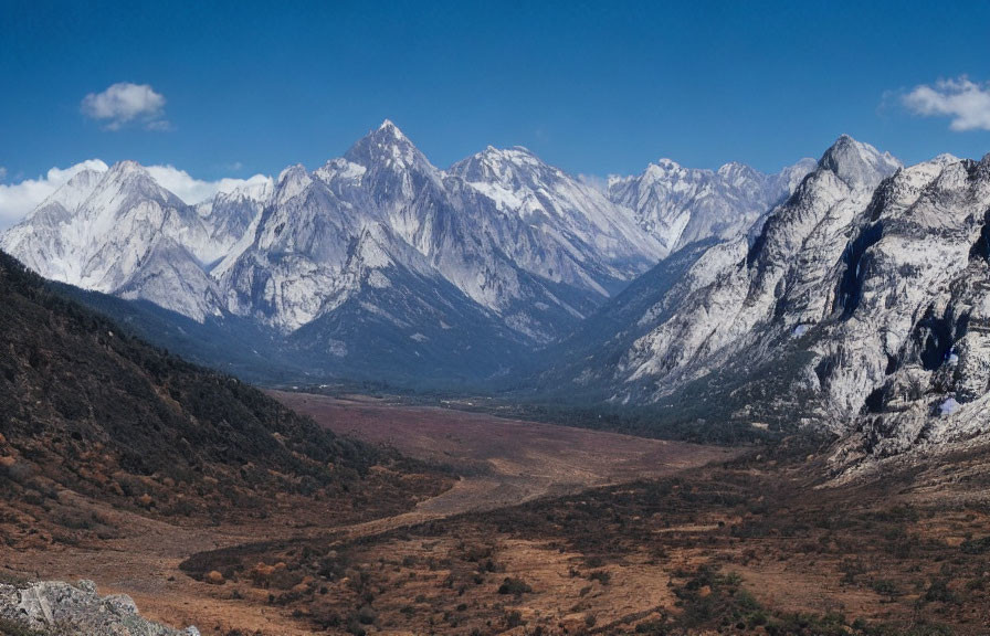 Snow-capped mountain range with valley and blue sky