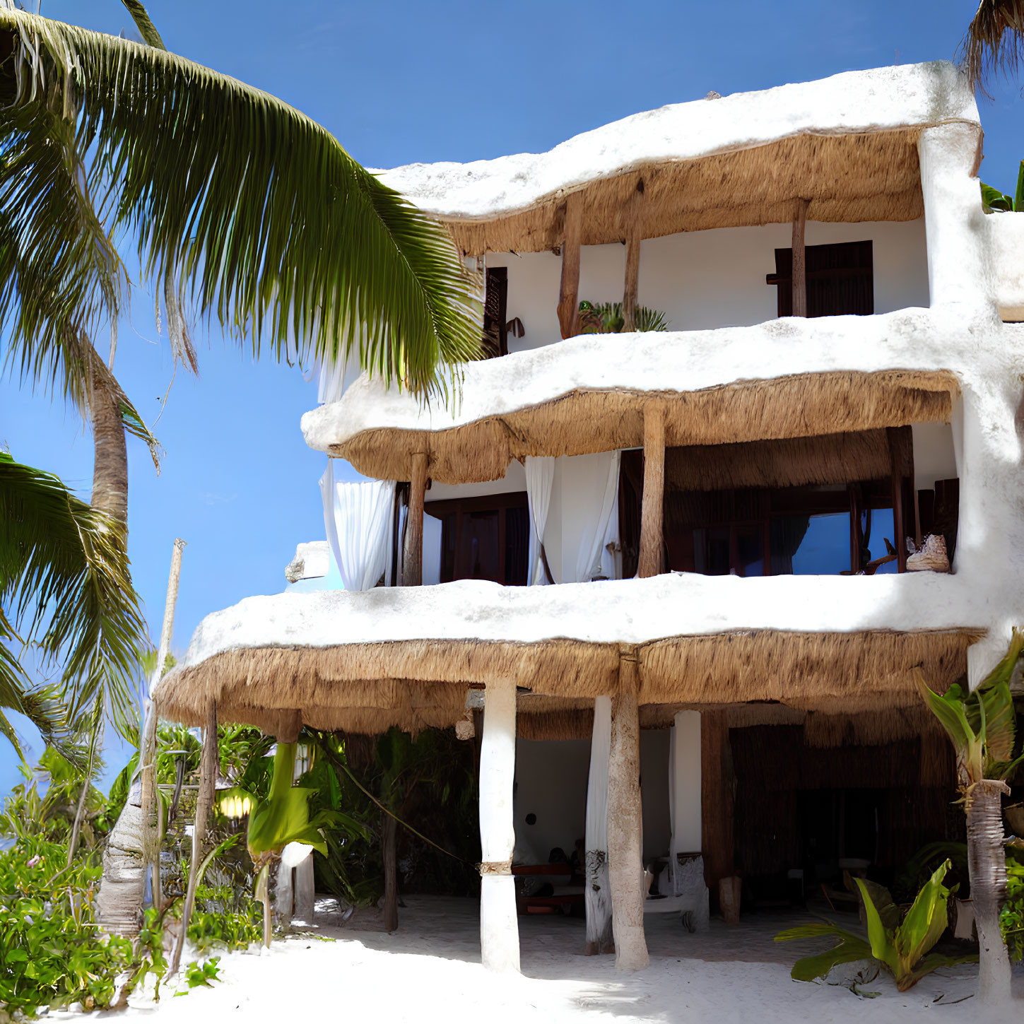 Tropical beachfront building with thatched roof and palm trees