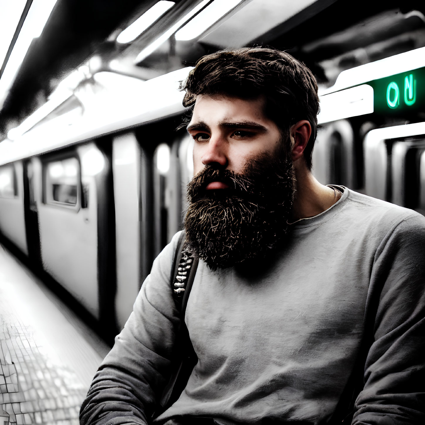 Bearded man with thoughtful expression at subway station as train arrives