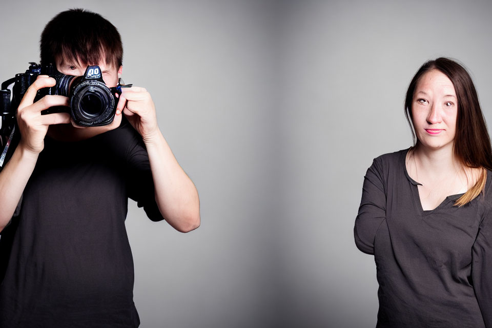 Man with camera covering face photographs skeptical woman against grey background