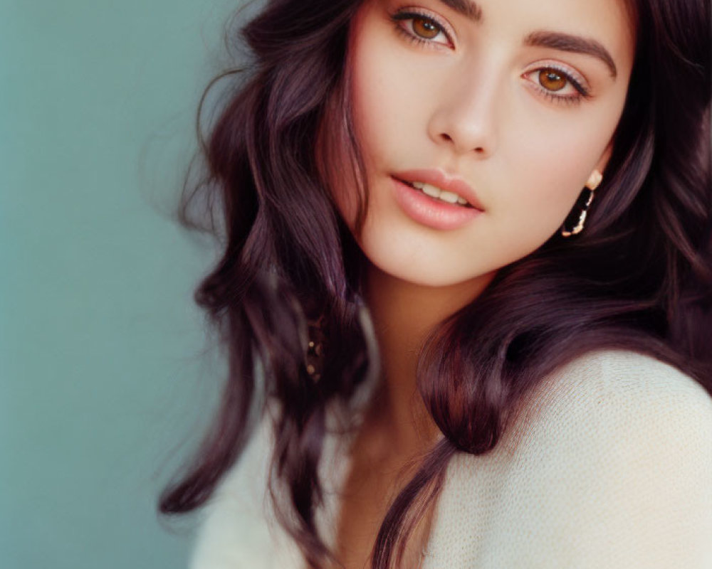 Portrait of Woman with Long, Wavy Dark Hair and Hazel Eyes on Teal Background