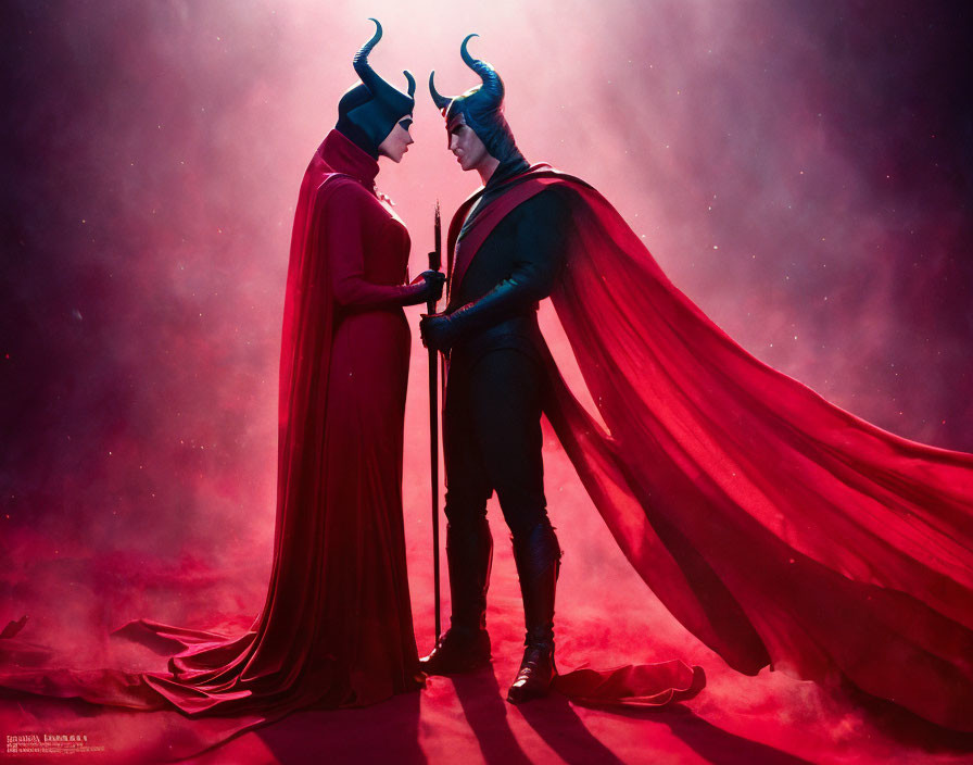 Two individuals in elaborate costumes with horns and capes in mystical setting