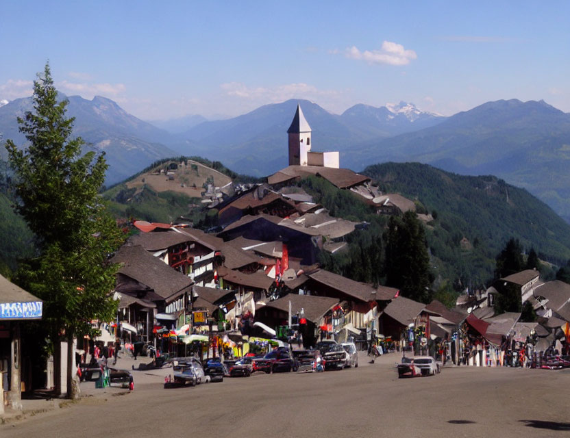 Scenic mountain village with church spire, bustling streets, and green slopes