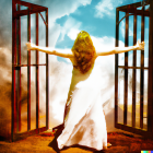 Woman in flowing white dress between open metal gates in scenic landscape