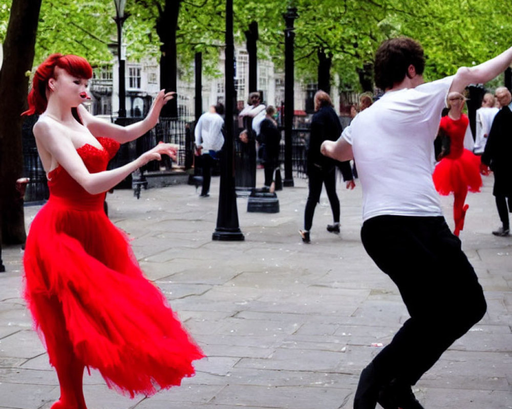 Outdoor couple dancing: woman in red dress, man in white shirt, others in background.