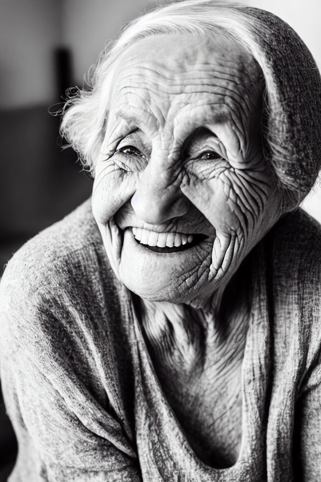 Elderly woman in headscarf smiling in black and white portrait