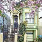 Victorian house with pastel green facade and cherry blossoms