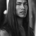 Monochrome digital painting of a man with long hair and tribal accessories