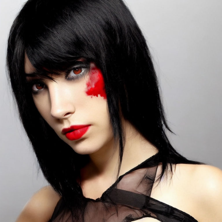 Intense gaze with red eye makeup and black hair on grey background