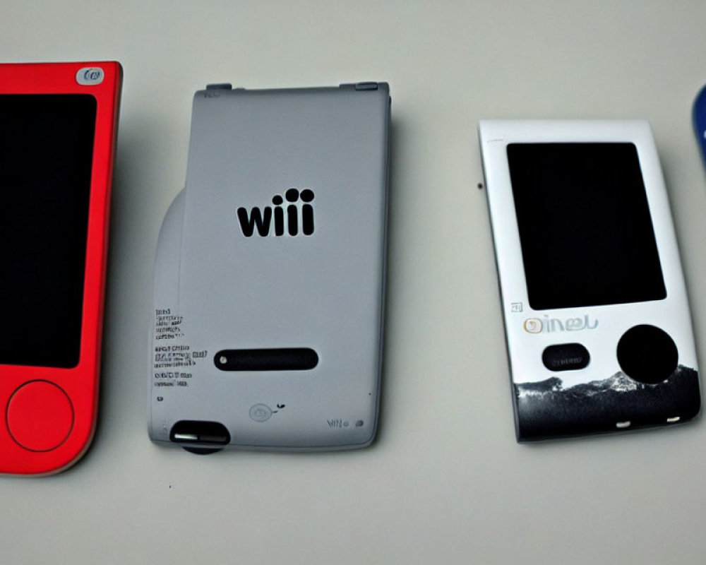 Red Portable Console, Grey Wii U GamePad, Blue Handheld Device on White Surface