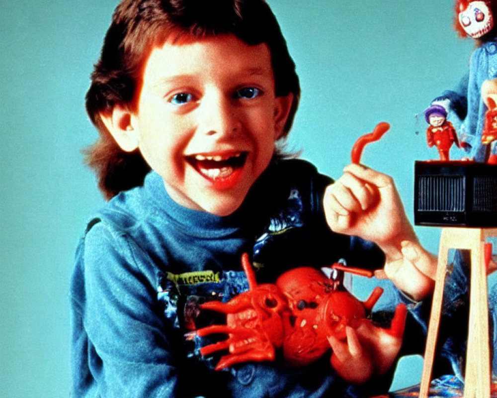 Smiling boy with toy and clown puppet on blue backdrop