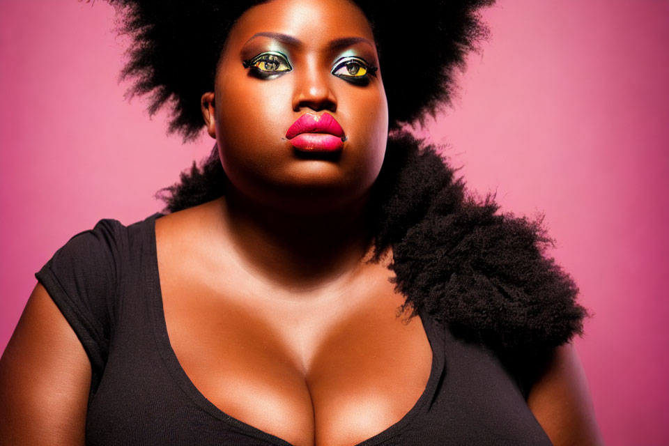 Confident woman with striking makeup and afro on pink background