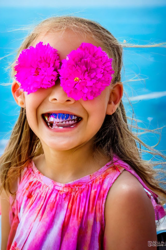 Smiling girl with pink flowers and tie-dye dress on blue background