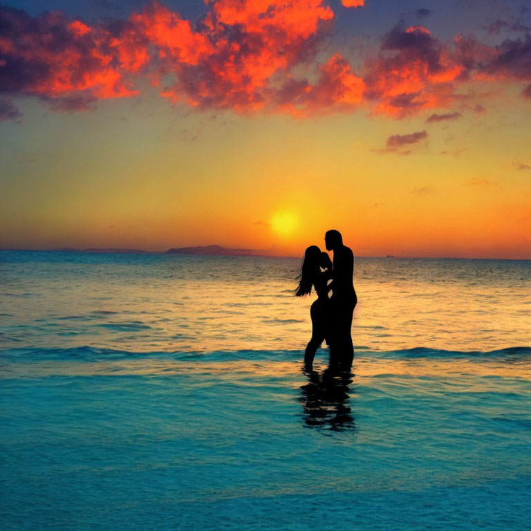 Silhouette of couple embracing in shallow water at vibrant sunset