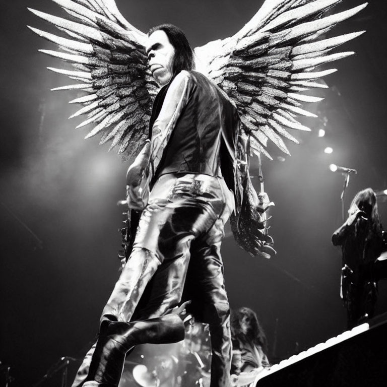 Person with Large Wing Props in Dark Clothing and Dramatic Makeup on Stage