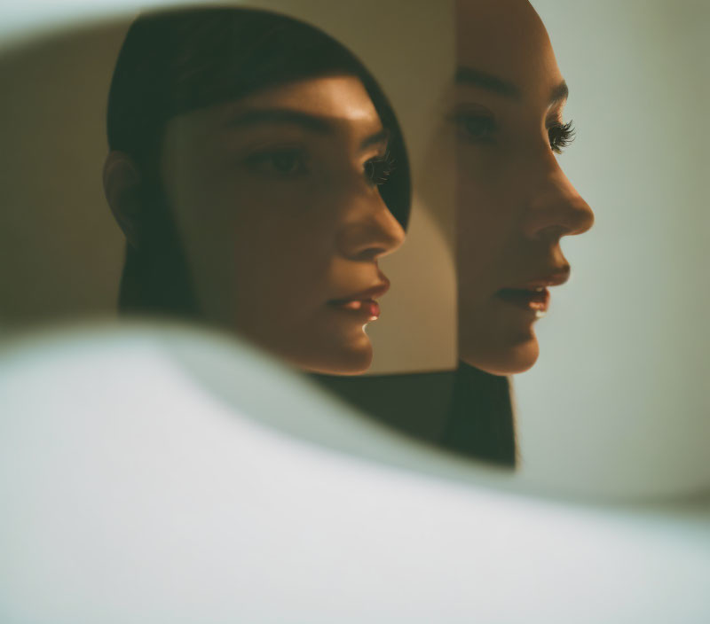 Woman Contemplating Reflection in Dimly Lit Mirror