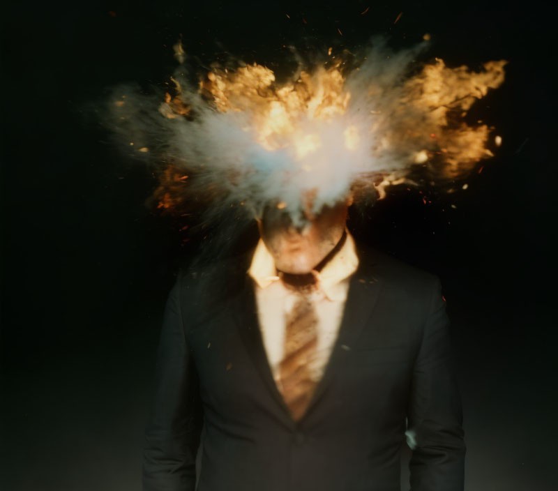 Person in suit obscured by explosive burst of fire and smoke