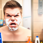 Man grimacing with electric razor sparks on cheek