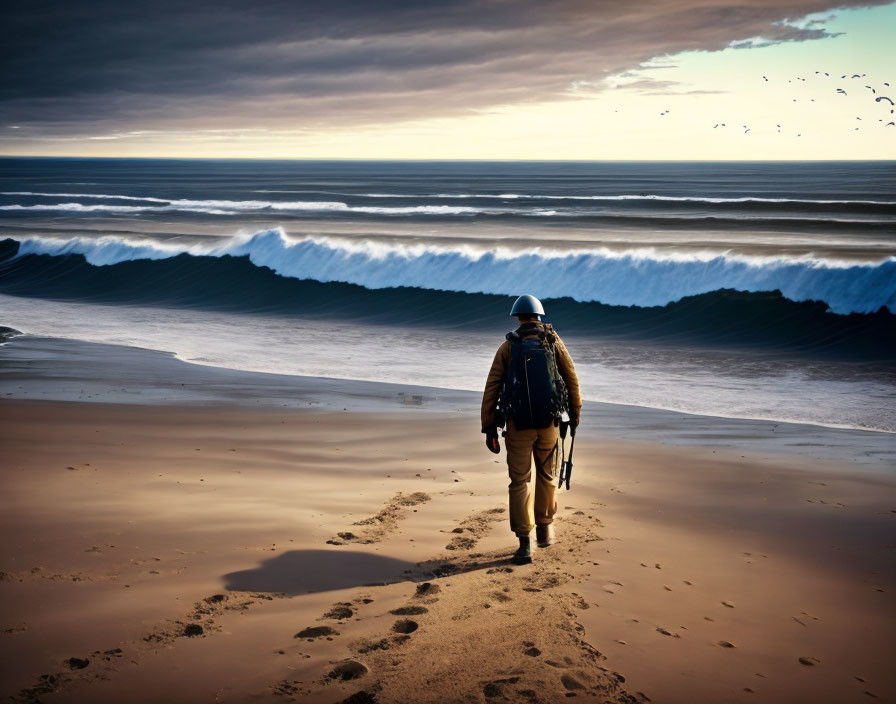 Outdoor gear wearer walks on beach with crashing waves and birds in sky