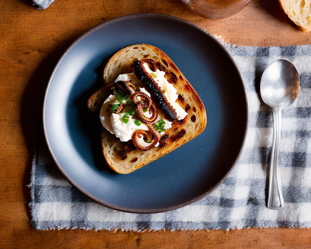 Grilled octopus tentacle on creamy spread toast with coffee and utensils