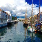 Colorful Buildings and Sailboats on Canal with Rowing People