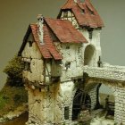 Stone cottage with towers, arched entryways, and ivy under cloudy sky