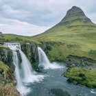 Scenic landscape with waterfall, fishing person, boat, and mountain peak