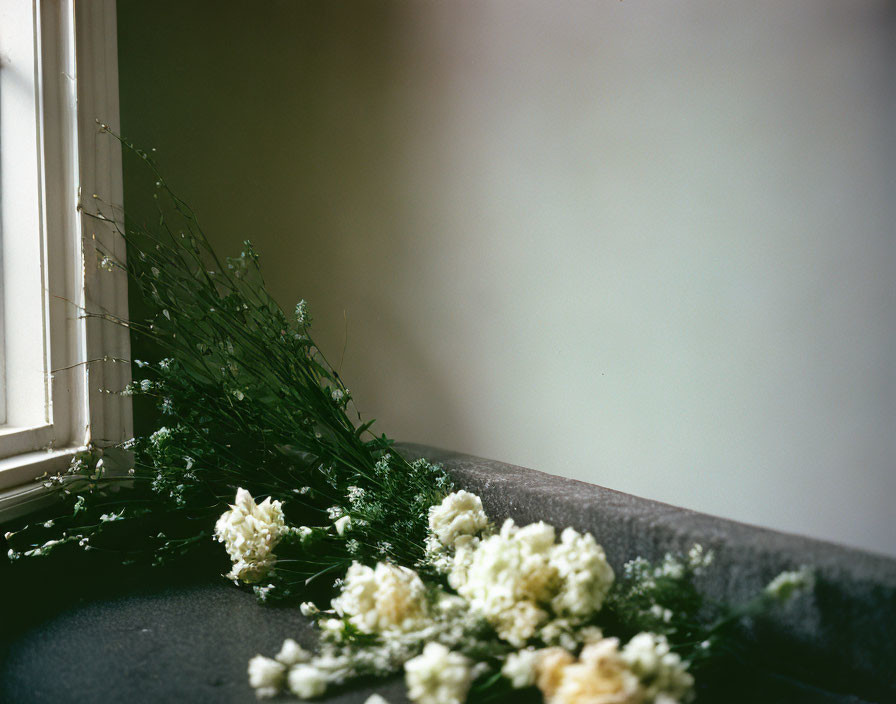 White Flowers and Greenery on Gray Surface in Soft Natural Light