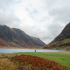 Tranquil landscape with person in red by reflective lake