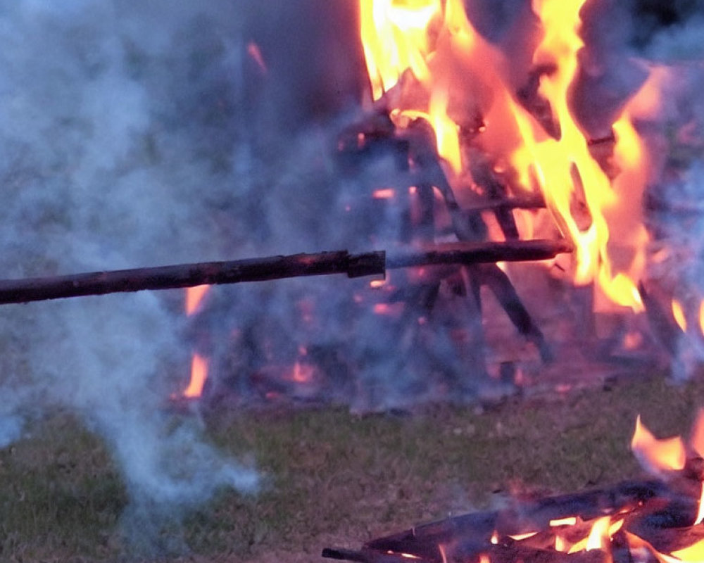 Burning wooden sticks close-up over outdoor bonfire