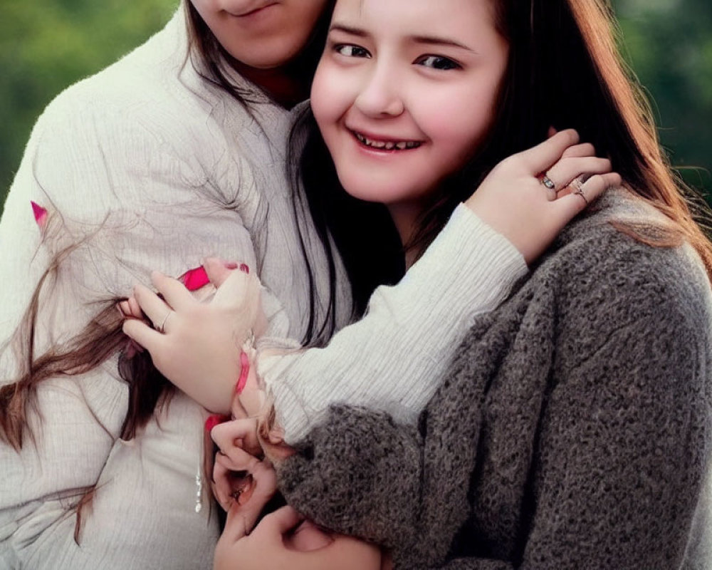 Smiling individuals in cozy sweaters with nose piercing, embracing in front of blurred green background