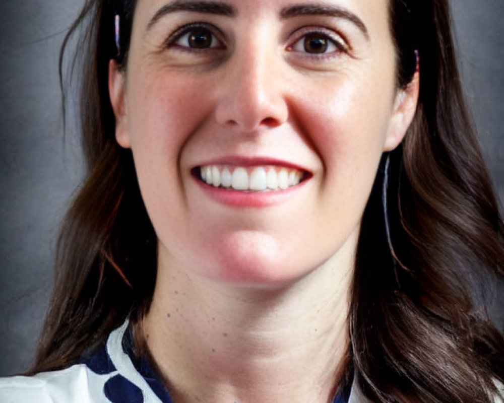 Smiling woman with dark hair in white and blue top and earrings