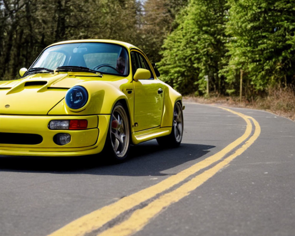 Bright Yellow Sports Car Driving on Asphalt Road Amid Green Trees