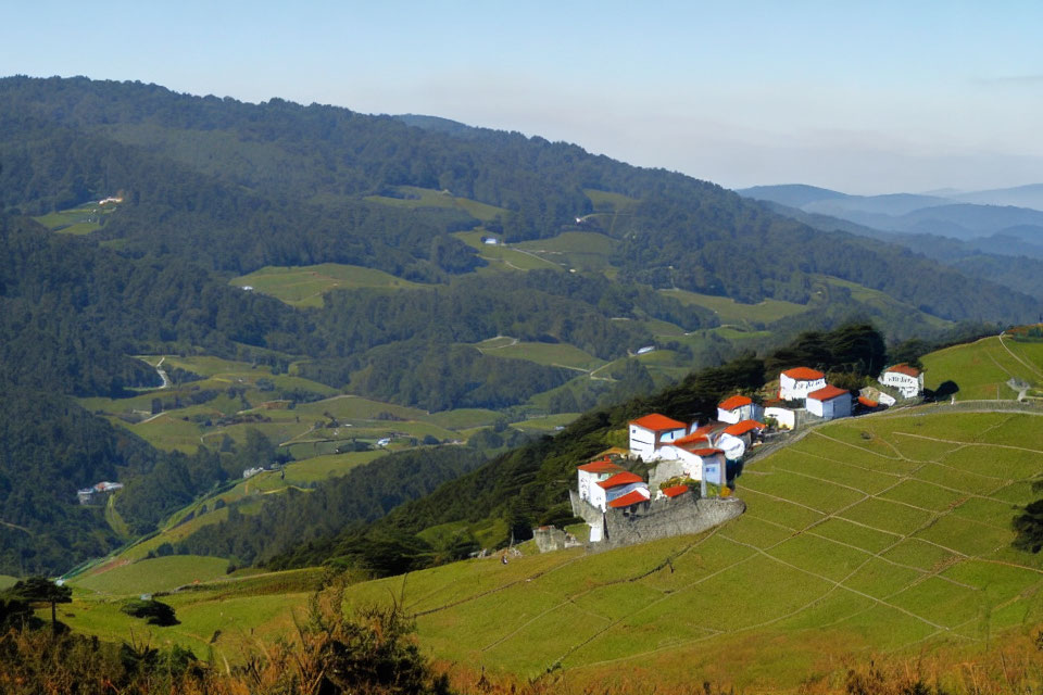 Scenic white houses on lush green hills with terraced fields and mountain backdrop