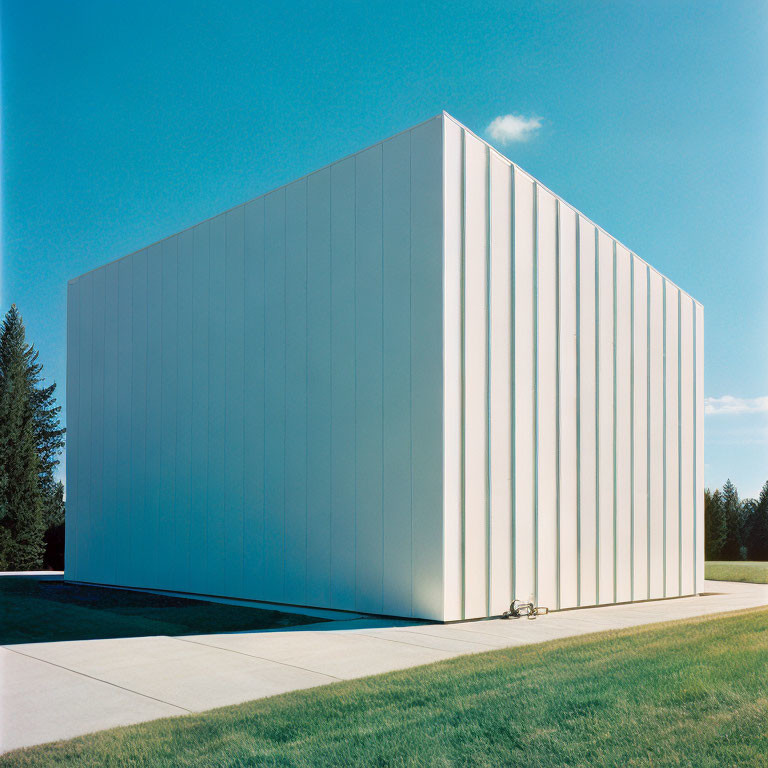 Modern minimalist building with flat façade and vertical lines against blue sky and green lawn