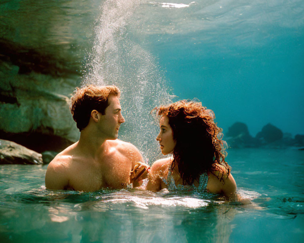 Couple holding hands by sunlit water with splash