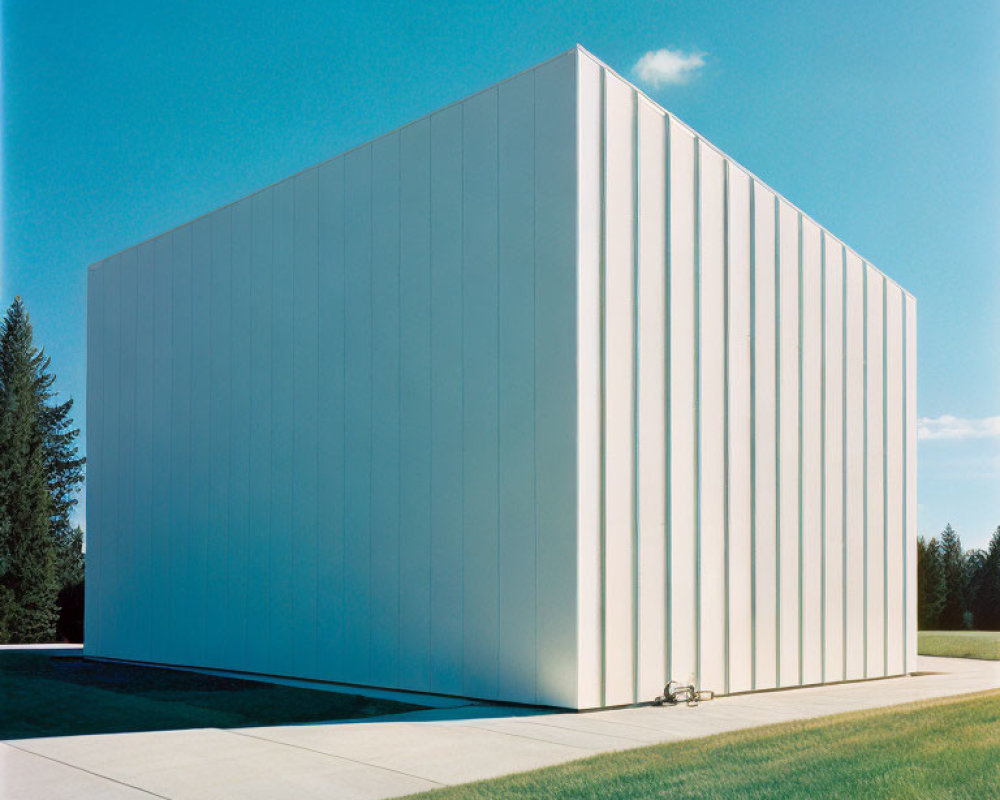 Modern minimalist building with flat façade and vertical lines against blue sky and green lawn