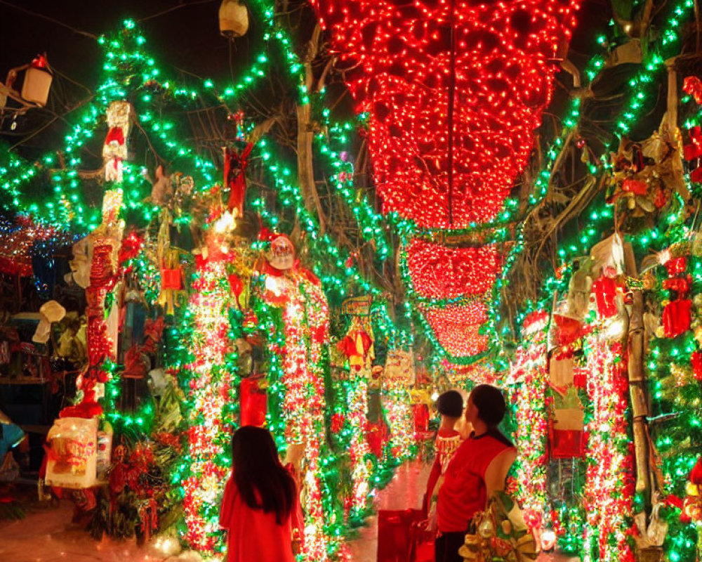 Nighttime Christmas lights display with people walking through festive outdoor area