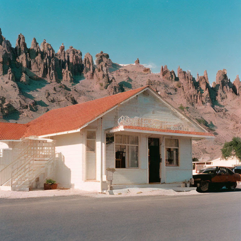 Vintage white building, classic car, mountains backdrop.