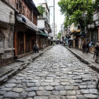 Historical village scene: cobblestone street, old houses, greenery & mist